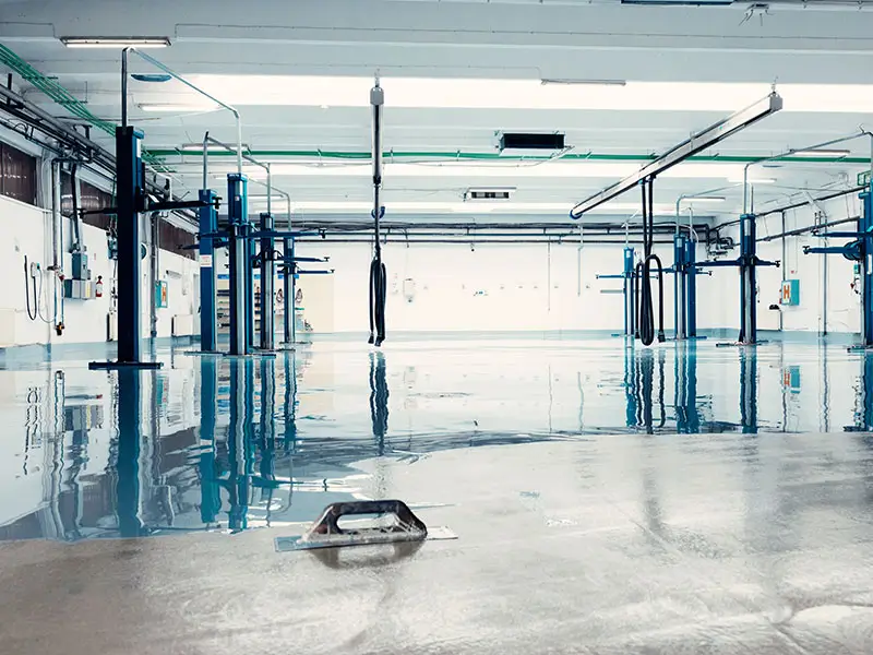 finishing new shiny epoxy floor in a car repair shop 