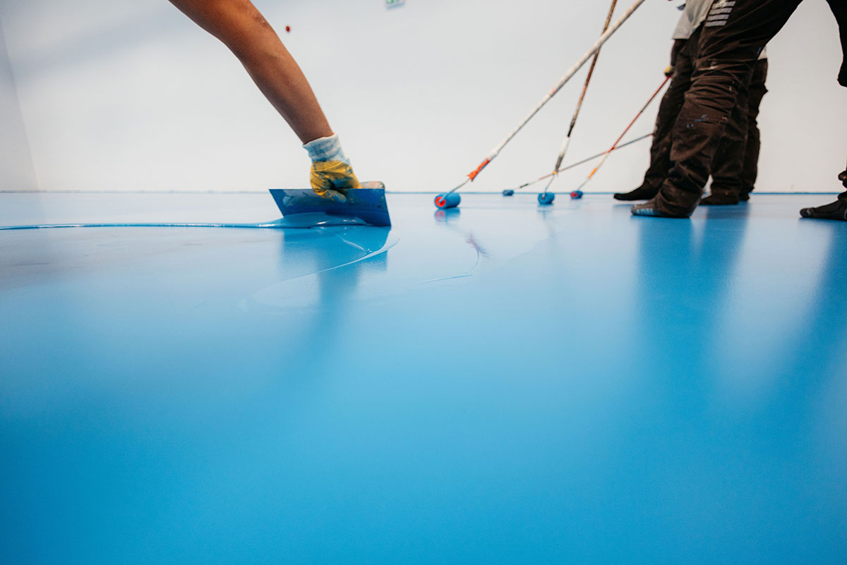 industrial workers applying blue epoxy resin on floor industrial workers applying blue epoxy resin on floor