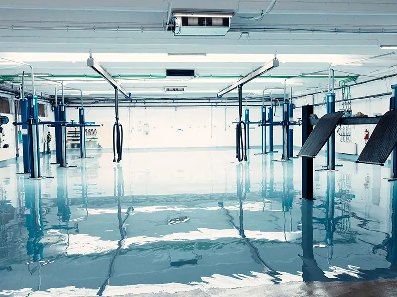 Empty car repair garage with hydraulic lifts and shiny epoxy floor