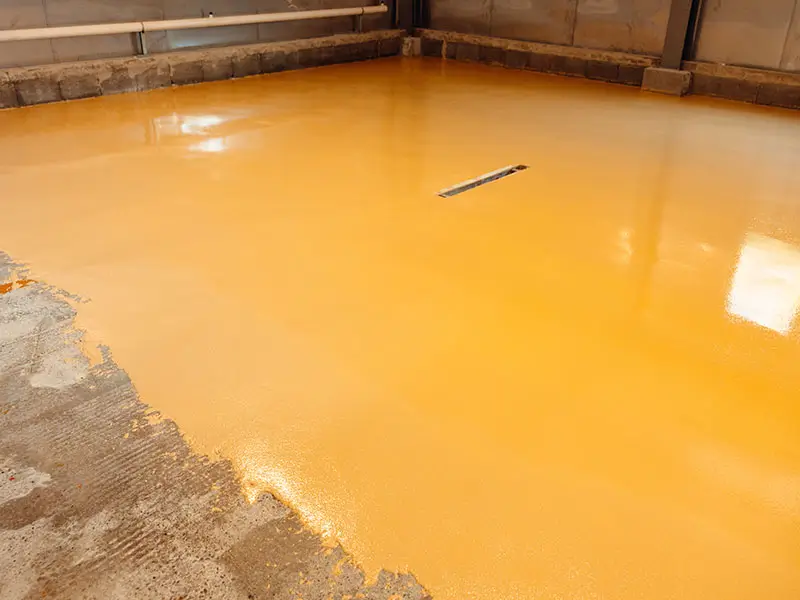 worker applying epoxy resin to concrete floor 